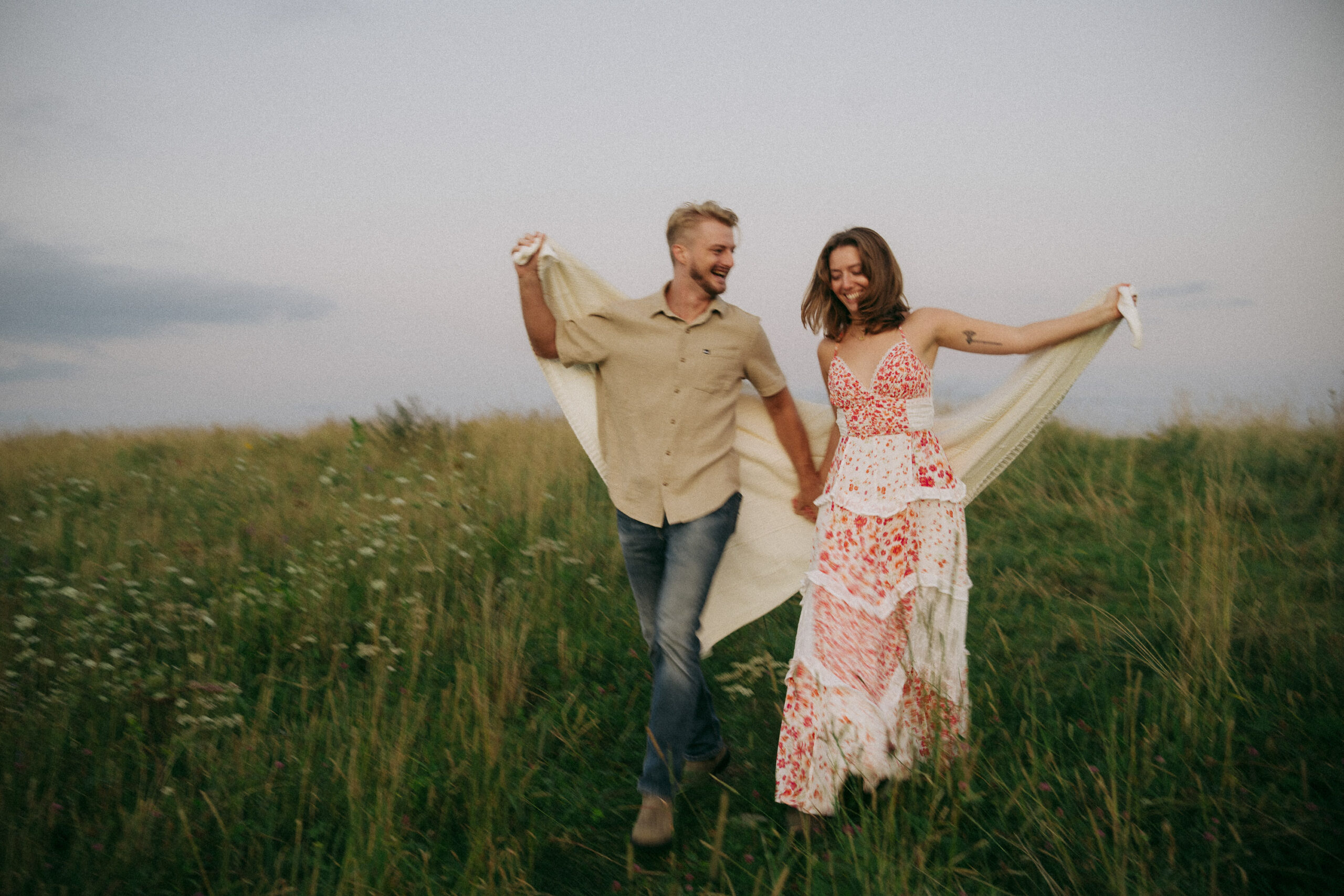 Couple running through a grassy field during an Asheville engagement session